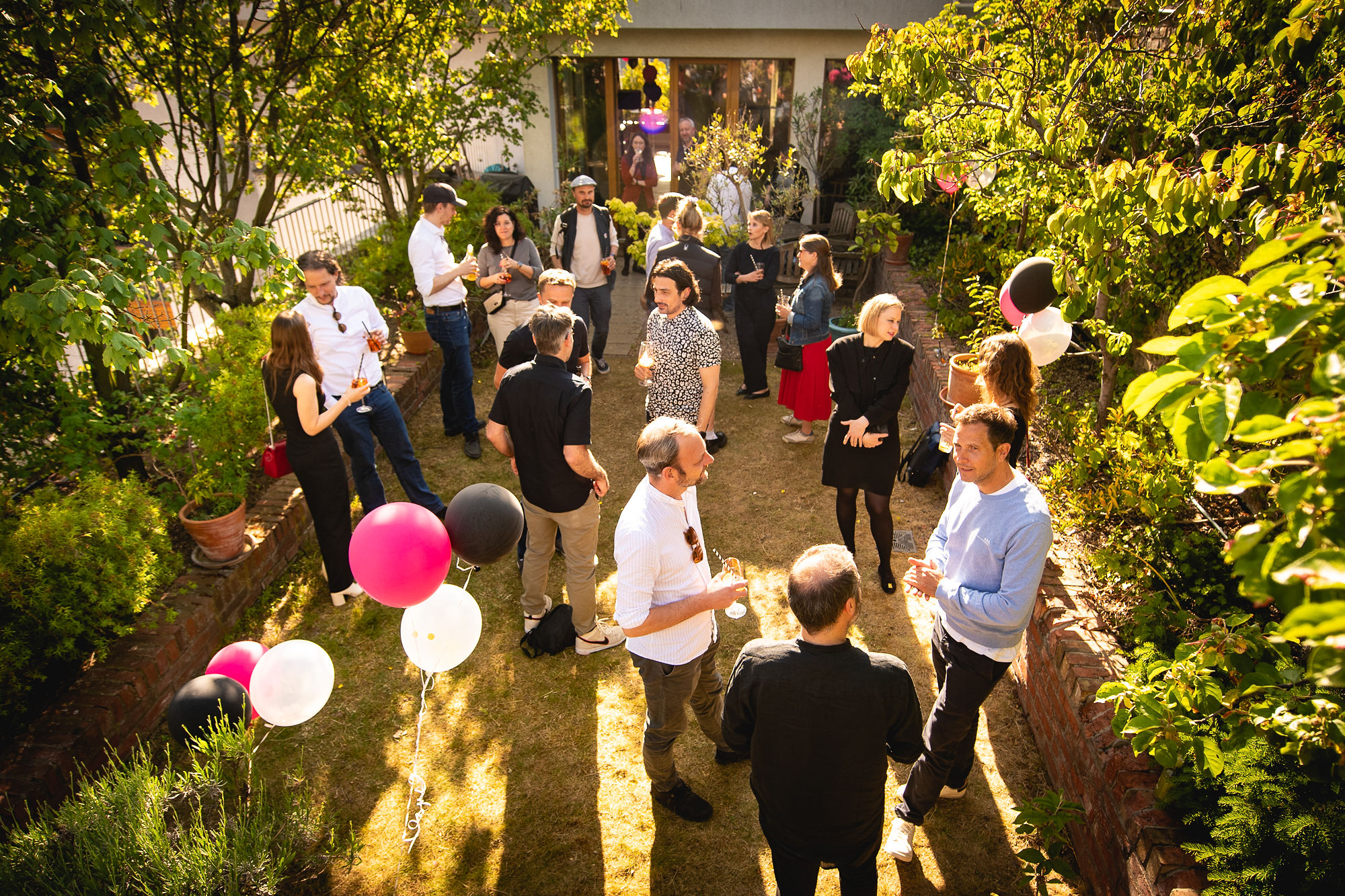 HelloCircle team and guests mingling in a sunlit garden with balloons